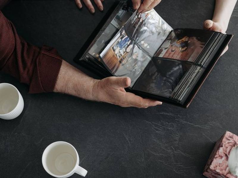 Hands turning the pages of a photo album on a table